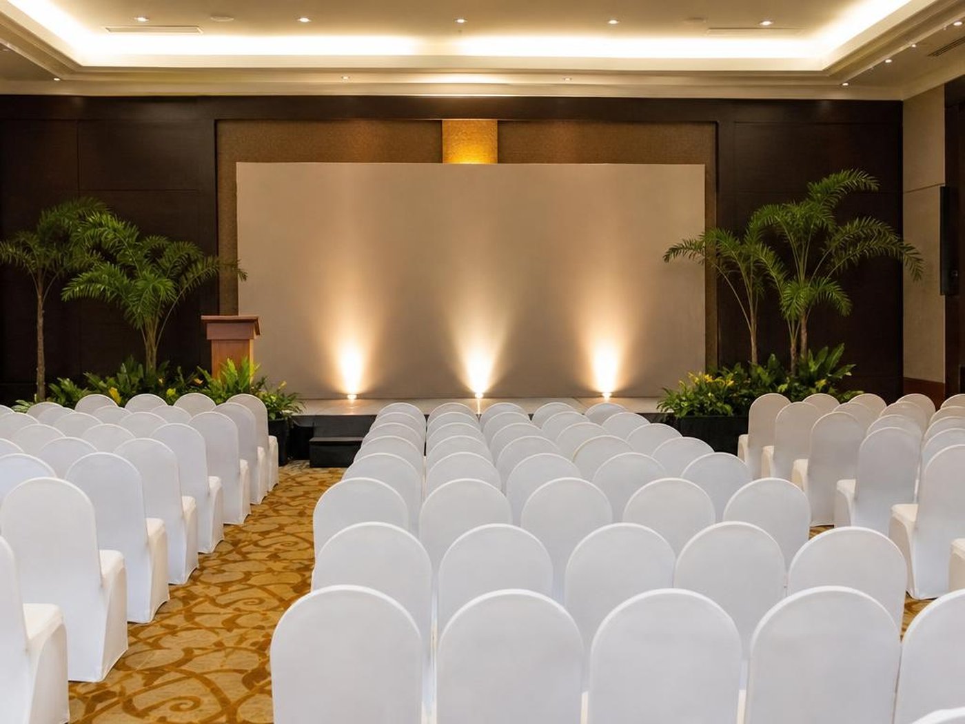 Hall seminar hotel dengan kursi bersarung dan panggung siap acara
