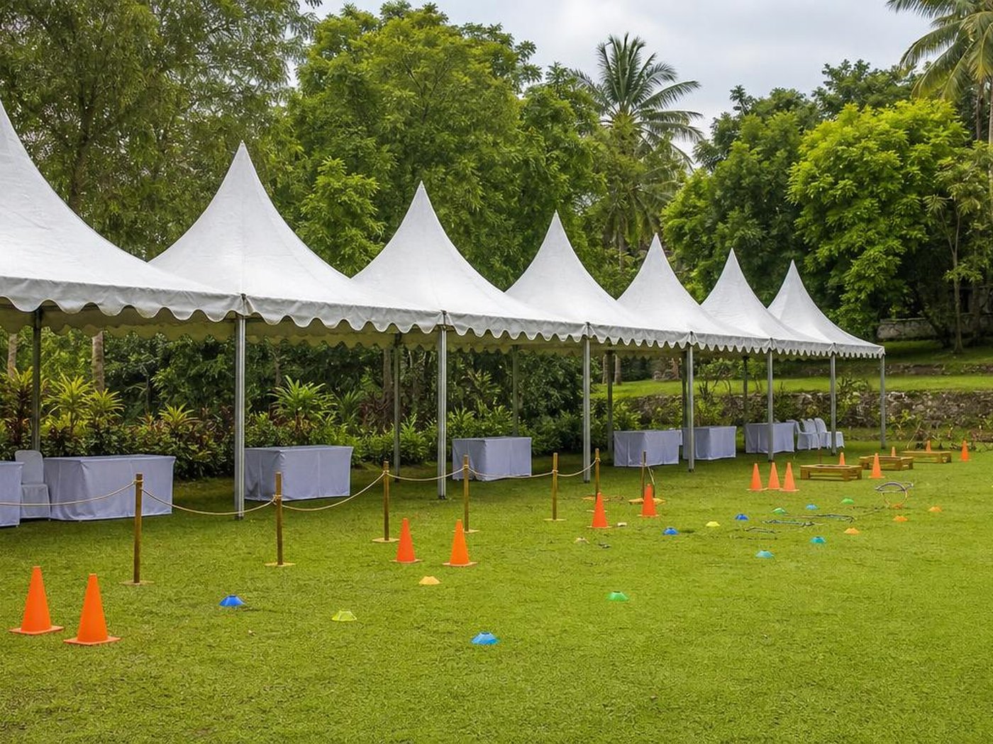 Area team building outdoor dengan tenda putih dan properti games di lapangan rumput