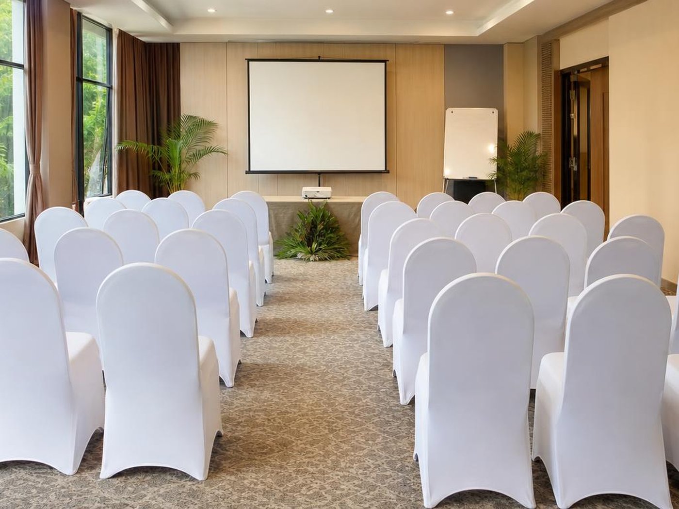 Ruang training kapasitas karyawan di hotel dengan kursi bersarung rapi menghadap layar proyektor