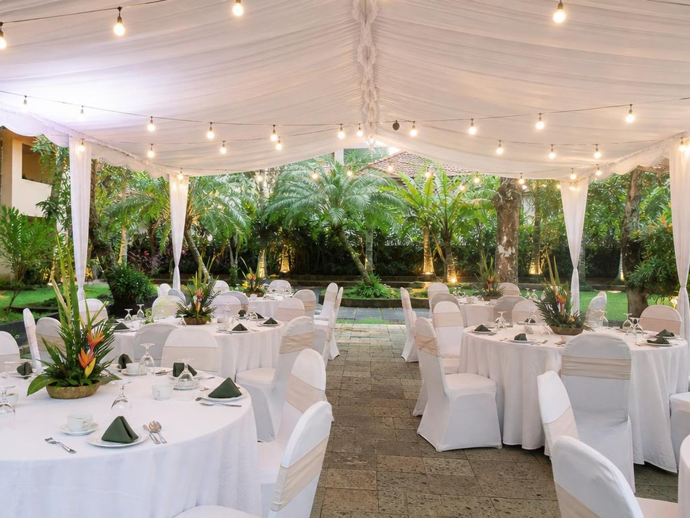 Setup gathering makan malam karyawan di tenda putih taman hotel dengan meja bundar dan kursi bersarung